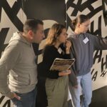 Un homme et deux femmes dans un labyrinthe aux murs noirs et blancs